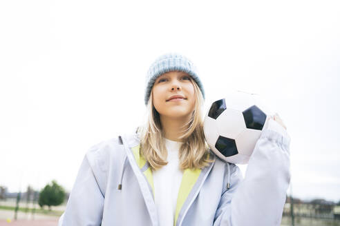 Mädchen stehend mit Fußball unter klarem Himmel - MDOF00455