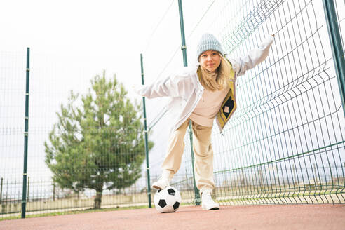 Blondes Teenager-Mädchen spielt mit Fußball auf dem Spielplatz - MDOF00456