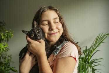 Smiling girl stroking cat at home - OSF01261