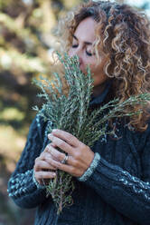 Mature woman with eyes closed standing with twigs - SIPF02875