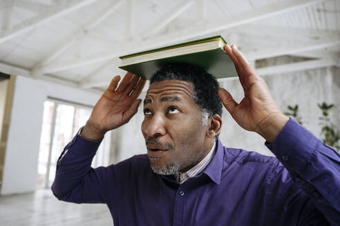 Älterer Mann balanciert Buch auf dem Kopf - EYAF02423