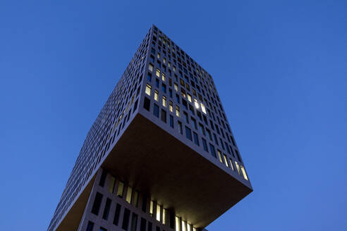 Deutschland, Bayern, München, Tiefblick auf modernes Bürogebäude in der Abenddämmerung - MAMF02353