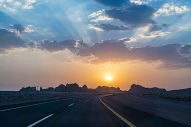 Saudi-Arabien, Al-Ula, Sonnenuntergang über leerer Landstraße - RUNF04880