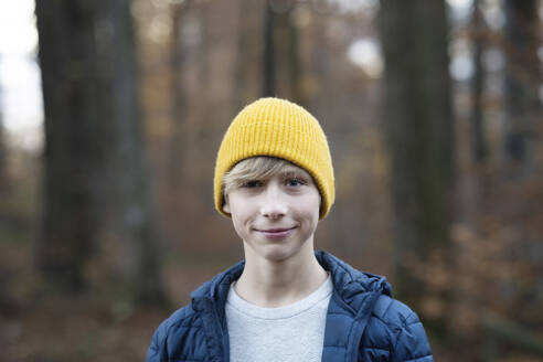 Lächelnder Junge mit gelber Strickmütze im Wald - NJAF00109