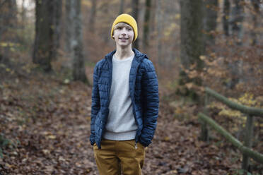 Smiling boy with hands in pockets at autumn forest - NJAF00110