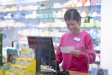 Zufriedene Apothekerin bei der Prüfung eines Rezepts im Sanitätshaus - NJAF00117