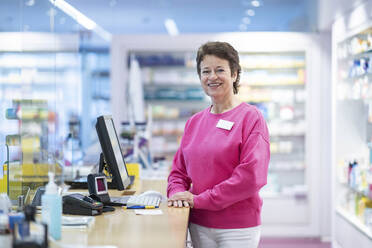 Glückliche Apothekerin lehnt sich auf den Schreibtisch - NJAF00122