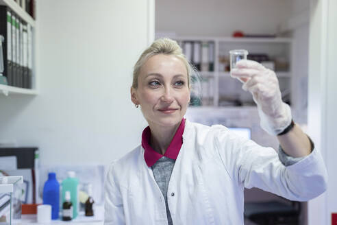 Smiling scientist examining liquid at laboratory - NJAF00129