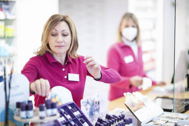 Pharmacist arranging medicines on rack at medical store - NJAF00137
