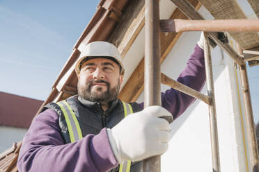 Smiling construction worker holding ladder - OSF01263