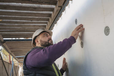 Bauarbeiter bei der Prüfung einer Wand aus Styropor auf der Baustelle - OSF01273