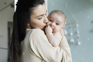 Mother kissing baby boy at home - TYF00532