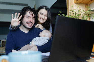 Happy father and mother with baby boy talking on video call through laptop - TYF00547