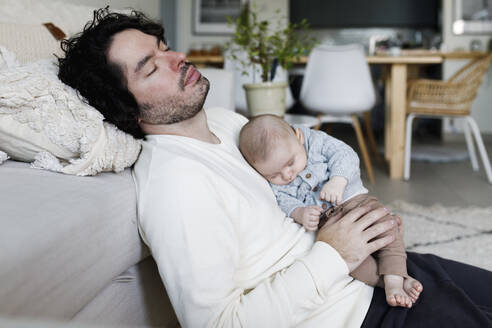 Father and baby boy sleeping together in living room at home - TYF00548