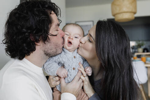 Father and mother kissing baby boy at home - TYF00552