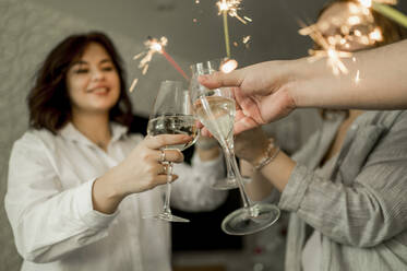 Glückliche Freunde, die zu Hause mit einem Glas Sekt und Wunderkerzen feiern - ANAF00764