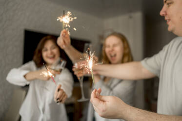 Cheerful friends having fun with sparklers at home - ANAF00765