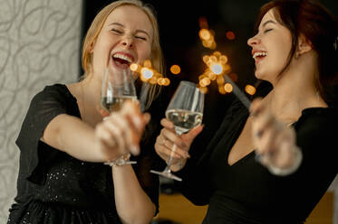 Cheerful friends celebrating Christmas with champagne glasses and sparklers - ANAF00772
