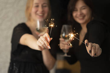 Happy friends celebrating Christmas with champagne glasses and sparklers - ANAF00773