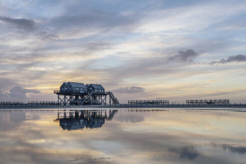 Deutschland, Schleswig-Holstein, St. Peter-Ording, Wolken über Stelzenhäusern an der Küste in der Abenddämmerung - KEBF02541