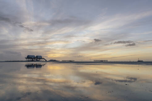 Deutschland, Schleswig-Holstein, St. Peter-Ording, Wolken über Stelzenhäusern an der Küste in der Abenddämmerung - KEBF02542