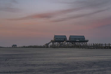 Deutschland, Schleswig-Holstein, St. Peter-Ording, Stelzenhäuser an der Küste in der Abenddämmerung - KEBF02543