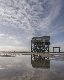 Deutschland, Schleswig-Holstein, St. Peter-Ording, Wolken über Küstenstelzenhaus in der Morgendämmerung - KEBF02548