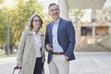 Thoughtful businesswoman and colleague standing on footpath - RORF03270