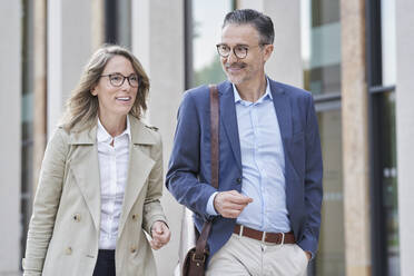 Happy mature business people walking together outside building - RORF03282