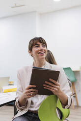 Smiling businesswoman holding tablet in office conference room - PNAF04699