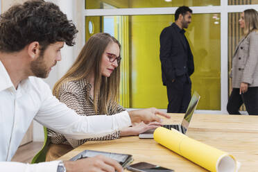 Geschäftskollegen im Büro arbeiten gemeinsam an einem Laptop - PNAF04715