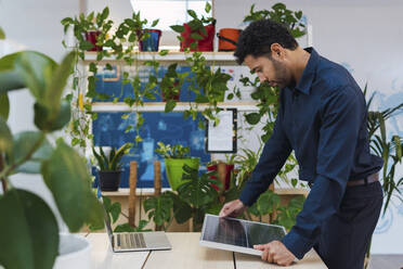 Businessman in office looking at solar panel - PNAF04771