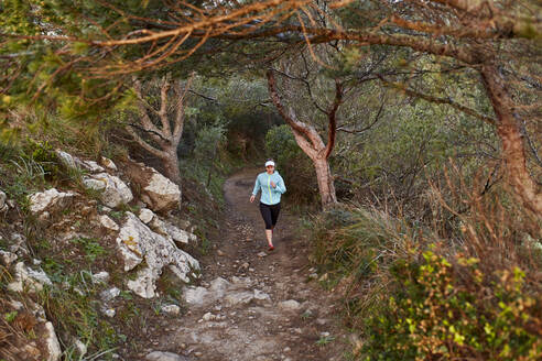 Sportliche Frau beim Laufen im Wald am Morgen - JPTF01216