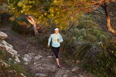 Woman running on dirt road in morning - JPTF01218