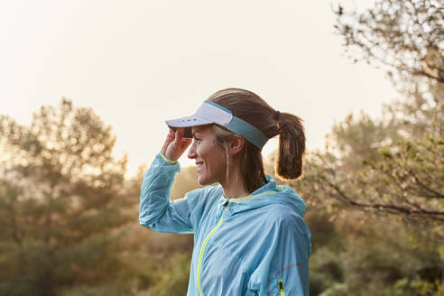 Happy woman adjusting visor cap - JPTF01219