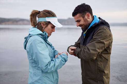 Paar stellt Smartwatch vor dem Laufen am Strand ein - JPTF01233