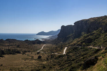 Oman, Dhofar, Salalah, Kurvenreiche Straße mit Küstenklippen im Hintergrund - RUNF04931