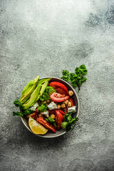 From above healthy salad with organic seasonal vegetables and avocado served on concrete table - ADSF42189