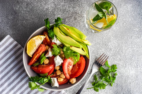 Von oben gesunder Salat mit biologischem Gemüse der Saison und Avocado, serviert auf einem Betontisch - ADSF42190