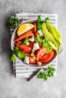 Von oben gesunder Salat mit biologischem Gemüse der Saison und Avocado, serviert auf einem Betontisch - ADSF42191