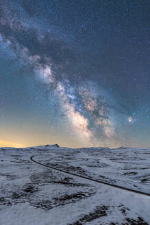 Drone Blick auf endlose schmale Straße geht zwischen gefrorenen Land unter funkelnden Himmel mit Galaxie - ADSF42324