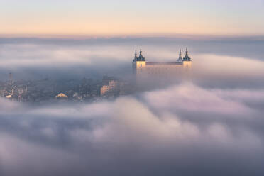 Luftaufnahme der Altstadt und des mittelalterlichen Palastes Alcazar de Toledo im Nebel bei farbigem Sonnenuntergang - ADSF42336