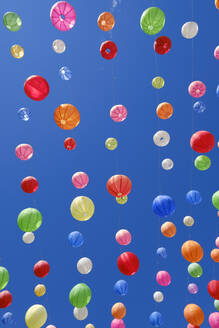 Germany, Bavaria, Kempten, Colorful paper lanterns hanging against clear blue sky - WIF04675