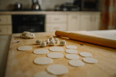 Rolling pin by dumplings on cutting board in kitchen at home - ANAF00780