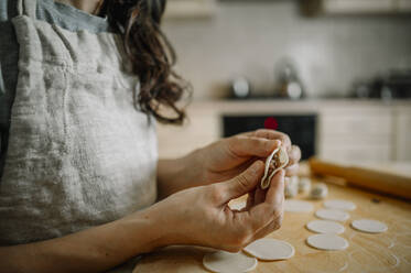 Woman preparing dumplings in kitchen at home - ANAF00781