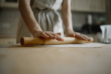 Woman rolling dough for dumplings in kitchen at home - ANAF00785