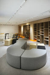 Stilvolle Einrichtung eines modernen Büros mit Stühlen und Hockern und leeren Regalen - ADSF42485