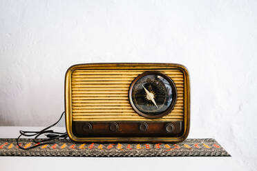 Vintage Holz Farbe Retro-Radio auf dem Tisch auf ornamentierten Stoff gegen weiße Wand platziert - ADSF42582