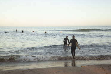 Menschen surfen auf dem Meer bei Sonnenuntergang - FOLF11931