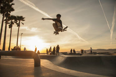 Teenage boy skating at skatepark during sunset - FOLF11952